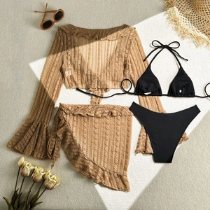Flat lay of a 4-piece bikini set with brown lace crochet cardigan and wrap skirt on beige