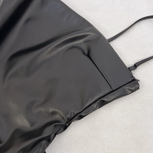 Dettaglio di un vestito in ecopelle nera con spalline sottili e cerniera laterale invisibile