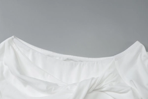 Gros plan détaillé du décolleté blanc élégant avec nœud torsadé sur cette robe d'été ajustée