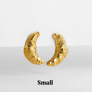 Close-up of small gold croissant earrings with a polished finish on white steps