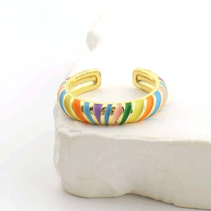 Dettaglio dell'anello dorato a C con strisce in smalto arcobaleno su pietra bianca