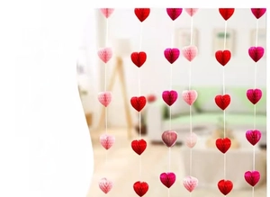 Close-up of heart-shaped honeycomb paper garlands in red and pink for festive decoration