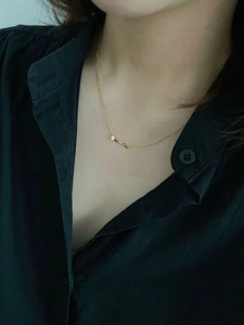 Gros plan d'un collier minimaliste en argent s925 doré avec pendentif barre et diamant