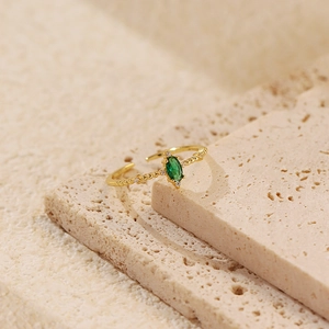 Detailed view of an adjustable gold ring with emerald green zircon on a stone pedestal