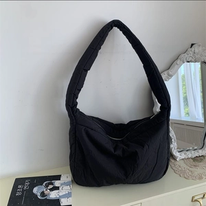 Detail of black quilted padded tote bag with soft texture and zipper on a stylish dresser