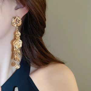 Gros plan de longues boucles d'oreilles dorées avec disques ronds en métal martelé texturé