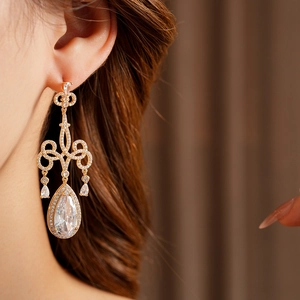 Détail de boucles d'oreilles gouttes en zircone étincelantes au design doré ajouré