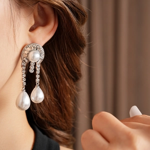 Dettaglio di orecchini in argento con diamanti geometrici e perle bianche sulla modella