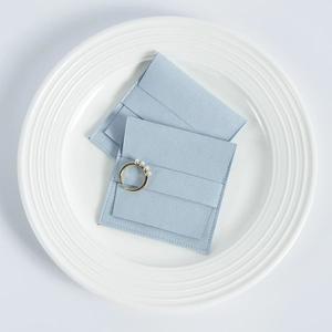 Detail of light blue microfiber suede jewelry pouch with gold pearl ring on ceramic plate