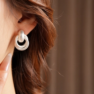 Detail of silver matte interlocking hoops earrings shown on model with soft lighting