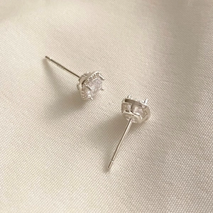 Macro shot of 925 silver square halo stud earrings with zircons on beige fabric