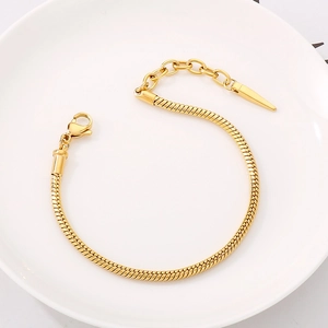Detail of gold snake bone chain bracelet with lobster clasp and cone pendant on white plate