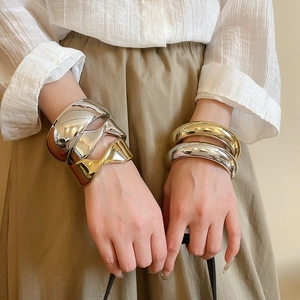 Detail of wide chunky gold and silver bangles with polished metallic mirror finish