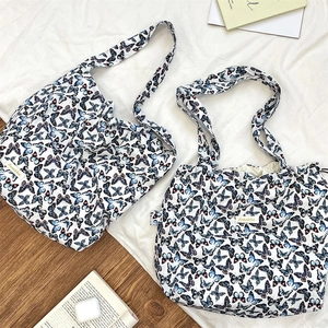 Detail of white butterfly print tote bags with drawstring closure on wooden background