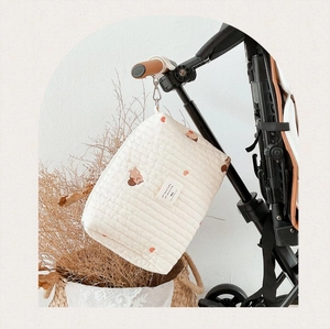 Quilted cotton diaper bag with brown bear embroidery hanging on a stroller handle