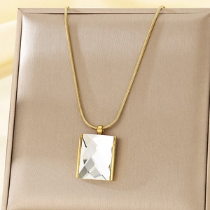 Detail of a golden snake chain necklace featuring a rectangular clear crystal pendant