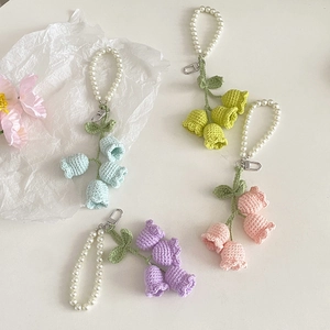 Detailed macro view of handmade crochet lily of the valley keychains in four pastel colors