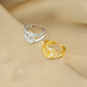 Crossed luxury zircon rings in gold and silver finish on silk fabric background