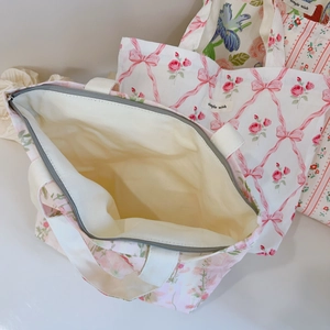 Gros plan d'un sac cabas fleuri rose montrant le zip gris et la doublure en toile