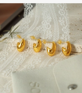 Detail of 18K gold plated bean stud earrings with velvet pouch on lace background