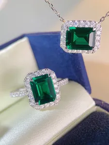 Macro detail of emerald-cut green gemstone necklace and ring set in a velvet gift box