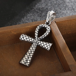 Gros plan du pendentif croix Ankh vintage en argent avec texture peau de serpent sur bois
