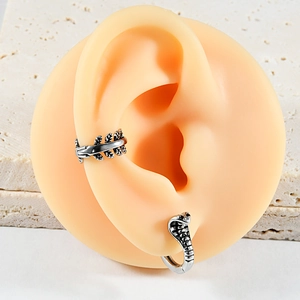Macro view of vintage silver snake earring and feather ear cuff on a model's ear