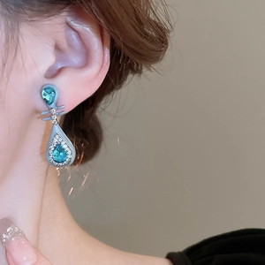 Detail of elegant teardrop earring with blue crystal and diamonds on model profile
