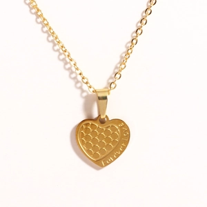 Macro detail of golden heart pendant with honeycomb texture and Forever Love engraving