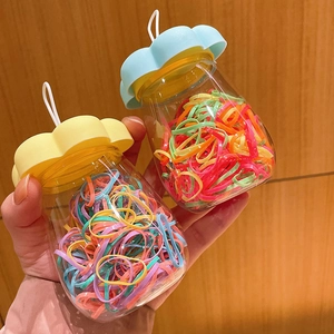 Detail view of colorful kids' elastic hair bands in cute flower-lid jars held by hand