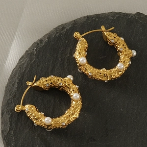 Détail de créoles plaquées or 18 carats avec texture irrégulière et incrustation de perles