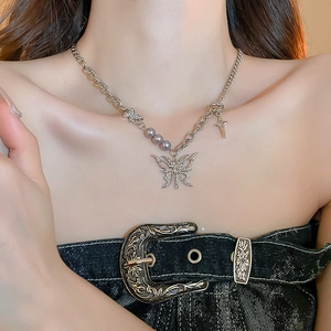 Lava butterfly necklace with silver cross pendant and grey-purple pearls on a female model