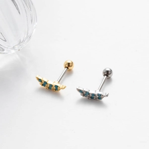 Detailed shot of gold and silver steel cartilage studs with blue inlaid stones
