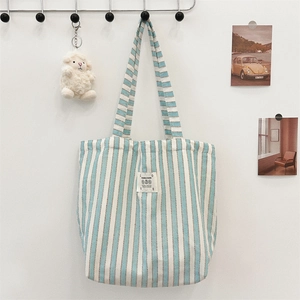 Detailed view of a blue striped canvas tote bag hanging on a wall for daily commute