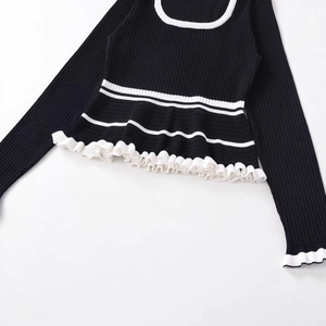 Chic black rib-knit top with contrast white trim and elegant ruffled hem detailing