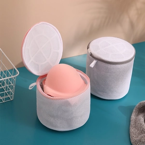 Cylindrical sandwich mesh laundry bags for bras with pink and gray zippers on blue background