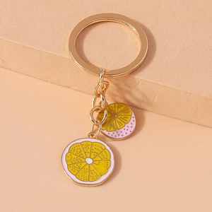 Detail of yellow and pink enamel lemon slice charms on a golden metal keychain