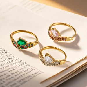 Elegante anello in acciaio al titanio dorato con gemme a forma di pera su un libro