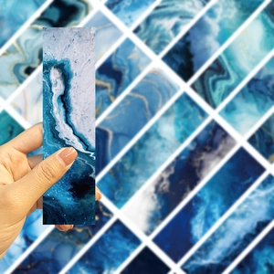 Detailed close-up of long blue fluid art ocean bookmarks held in hand showing texture