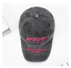 Détail d'une casquette en coton gris délavé avec broderie de lettres roses vives