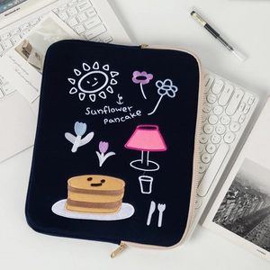 Detailed close-up of dark blue laptop sleeve featuring colorful embroidered sunflower pancake