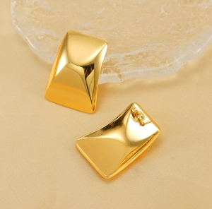 Close-up of gold plated stainless steel rectangular earrings with a polished convex surface