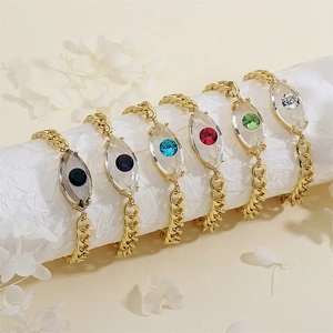 Makro-Detail goldener Panzerkettenarmbänder mit bunten Evil-Eye-Kristallanhängern