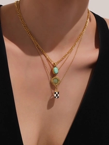 Detailed layered necklace featuring green gemstone, openwork circle, and checkerboard pendants