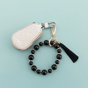 Détail de l'étui à clés en cuir crocodile blanc cassé avec dragonne à pompon noir