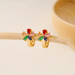 Macro detail of colorful floral earrings with vibrant zircon petals on a wooden branch
