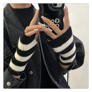 Close-up of black and white striped knitted arm warmers worn with a black denim jacket