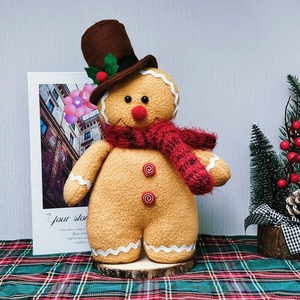 Gingerbread man plush doll with red knitted scarf and hat on festive wooden stand