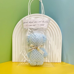 Close-up of a blue crochet bear doll in a clear PVC gift bag with decorative ribbons