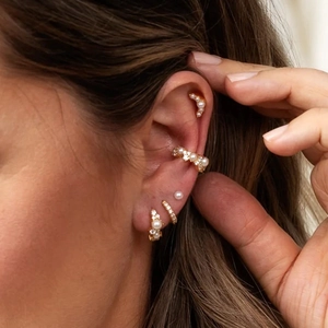 Detail view of s925 silver pearl and zircon earrings set worn on a female model ear